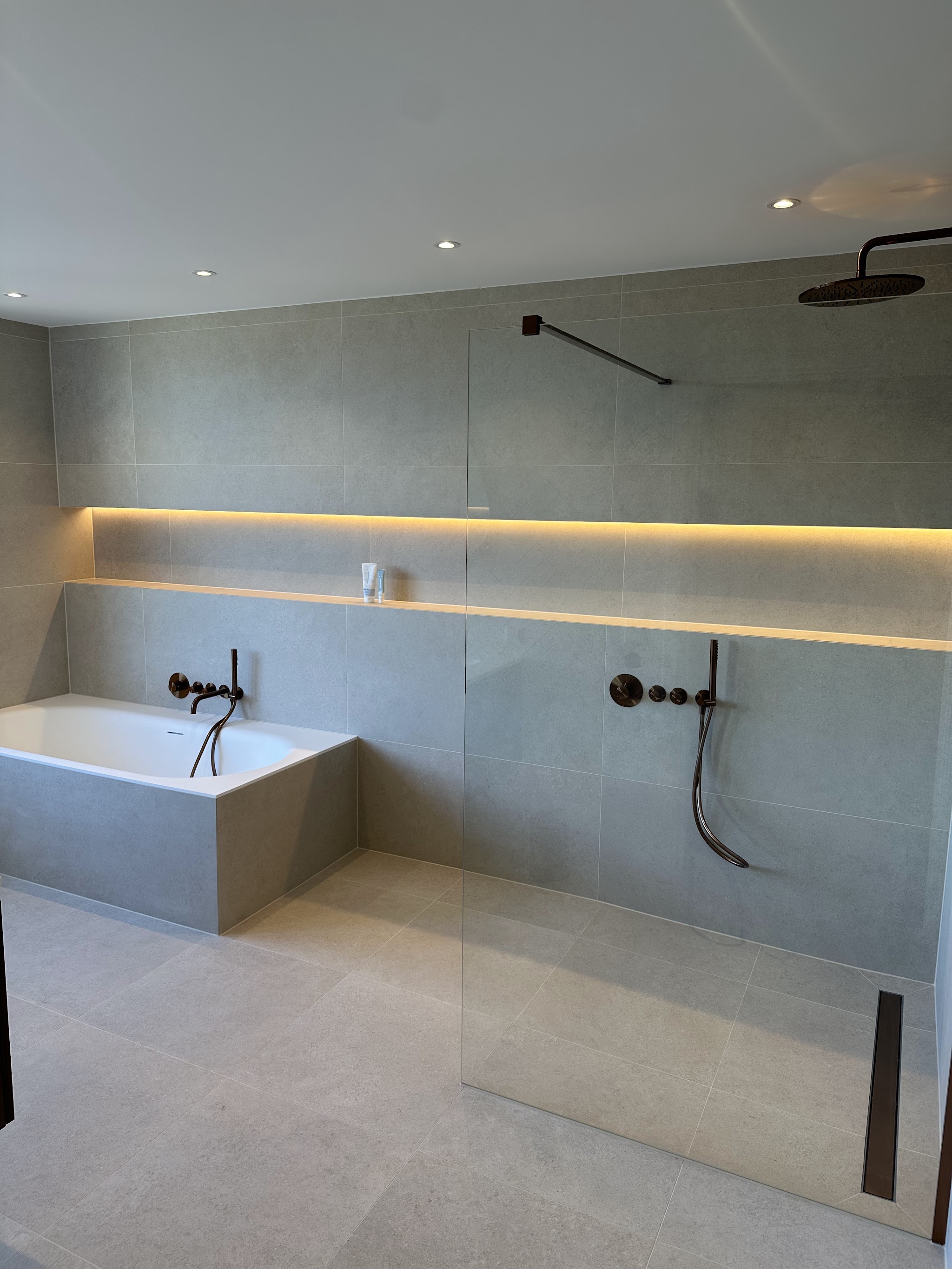 Inloopdouche met glazen wand, ligbad en LED-verlichting in de nis over de hele breedte