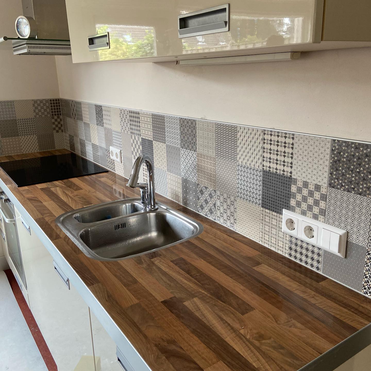 Keuken met een achterwand van patroontegels en een houtlook werkblad